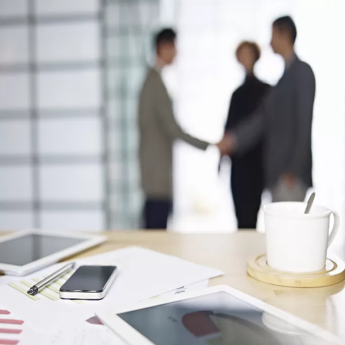 Two people inside of an office shaking hands.