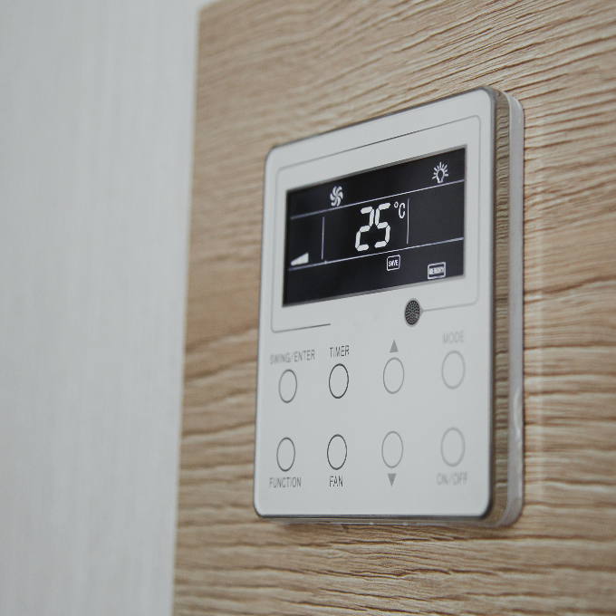 A thermostat installed onto a wooden wall.