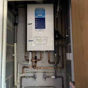 A commercial boiler installed inside of a storage cupboard.