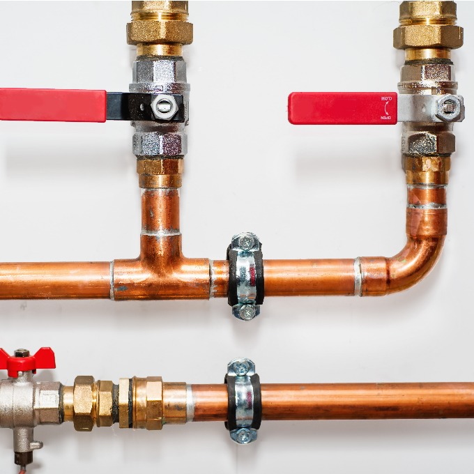 Copper pipes and valves on a white wall.
