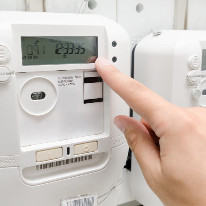 A finger points to a number displayed on an energy meter.