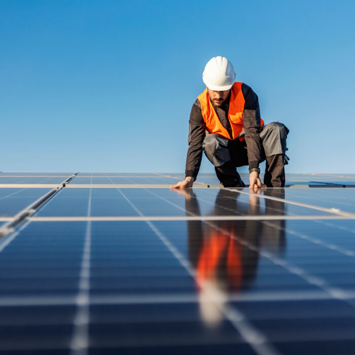 An engineer installs a new set of solar panels on a large roof.